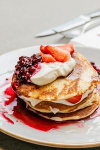 ein Stapel Pfannkuchen mit Obst auf einem Teller in der Unterkunft Designhotel Beila in Bilzen