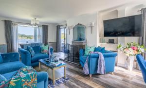 a living room with blue couches and a tv at Otterpoint Waterfront & Pool Retreat in Tayvallich