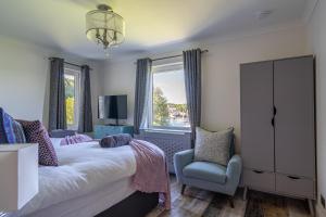a bedroom with a bed and a chair and a window at Otterpoint Waterfront & Pool Retreat in Tayvallich +43 photos