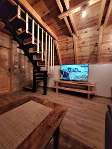 a living room with a tv and a wooden staircase at Koliba SAN in Žabljak