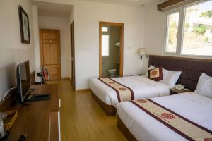 a hotel room with two beds and a television at Nhật Vy 1 Đà Lạt in Ấp Ða Lợi +14 photos