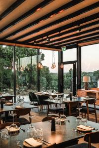 a restaurant with tables and chairs and large windows at L'École Villa Nature in Abrantes