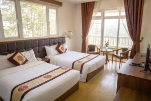 a hotel room with two beds and a window at Nhật Vy 1 Đà Lạt in Ấp Ða Lợi