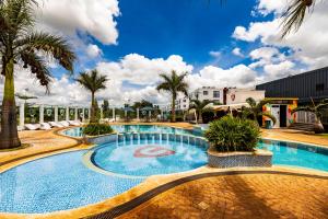 a large swimming pool with palm trees and buildings at 1 bedroom unit with a sunrise view in Tatu City
