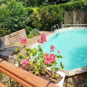 a swimming pool with a bench and flowers next to it at Chalet La Bachole - Chambre d'hôtes in Charancieu