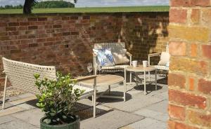 a patio with chairs and tables and a brick wall at Bluebell in Edlington