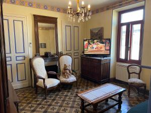 a living room with a tv and chairs and a table at Le Mas Ferrand in Graveson