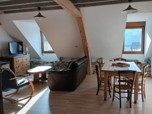 a living room with a black leather couch and a table at Le Som' des Pyrénées in Luz-Saint-Sauveur