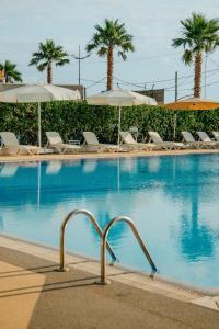 a swimming pool with chairs and umbrellas at Era Palace Gonio in Kvariati