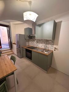 a kitchen with green cabinets and a sink and a table at B&B dell'Arco in LʼAquila