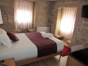 a bedroom with a large bed and two windows at Hotel Solar da Capela in Termas de Sao Pedro do Sul