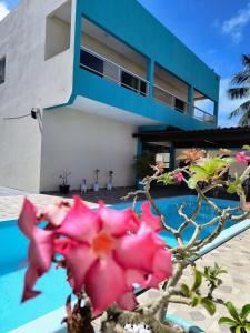 a house with pink flowers in front of a building at Pousada Donna Maraka in Porto De Galinhas