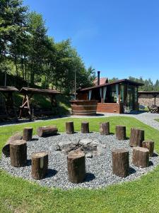a circle of logs in the grass with a house in the background at The Heaven Sibiu in Sebeşu de Sus