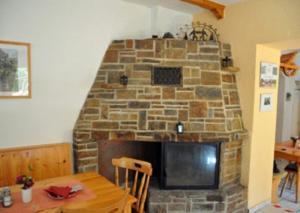 a stone fireplace in a living room with a wooden table at HerrBerge Pilgerglück in Eibenstock