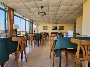 a dining room with tables and chairs and windows at Hotel Marsal in Antofagasta