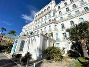 a large white building with palm trees in front of it at Palace Riviera Studio - Plages & Centre Menton in Menton