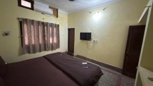 a bedroom with a bed and a window and a television at Hotel Golden Pearl in Rewa