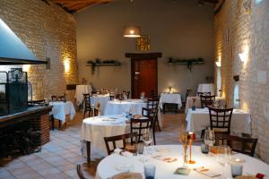 a dining room with white tables and chairs and a fireplace at Logis Insolites et Restaurant Domaine du Seudre in Saint-Germain-du-Seudre