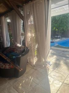 a porch with a chair and a window with a pool at Les Poiriers Rouges in Mauchamps