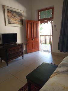 a living room with a door and a tv and a room with a bed at Green Olive Guesthouse in Robertson
