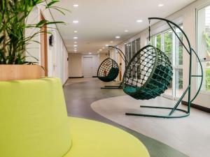 a hallway with chairs and plants in a building at Ibis Styles Campinas Alphaville in Campinas
