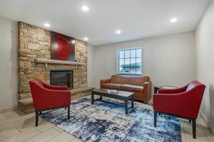 a living room with two red chairs and a fireplace at Red Roof Inn Charlestown in Charlestown