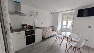 a white kitchen with a table and chairs in it at Praciña do olvido in Cee