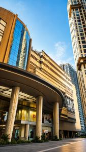 a large building with a curve in front of tall buildings at Transpark Cibubur by 21room in Kalimanggis