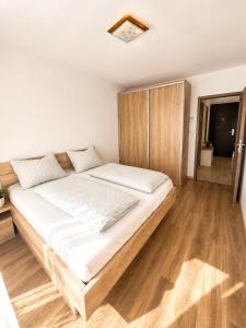 a large bed in a room with wooden floors at Apartment Centrum Orion in Dubnica nad Váhom