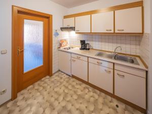a kitchen with white cabinets and a sink and a door at Appartementhaus Holmernhof I in Bad Füssing