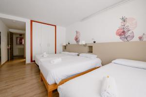 Zwei Betten in einem Zimmer mit weißen Wänden und Holzböden in der Unterkunft Hotel Terranova in Pas de la Casa