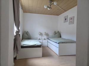 two beds in a room with white walls and wooden ceilings at Ferienwohnung Nele in Heimbach