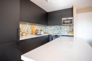 a kitchen with black cabinets and a white counter top at Modern 3 bedroom apartment - 4 minute walk from metro - top floor baclony view in Oslo +13 photos