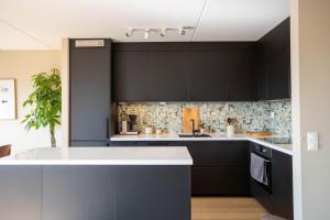 a kitchen with black cabinets and a white counter top at Modern 3 bedroom apartment - 4 minute walk from metro - top floor baclony view in Oslo