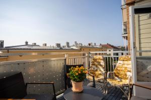 a balcony with chairs and a table with a vase of flowers at Modern 3 bedroom apartment - 4 minute walk from metro - top floor baclony view in Oslo