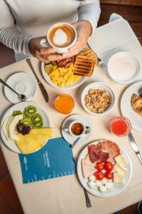 a person holding a cup of coffee on a table with breakfast foods at Hotel Les Jumeaux Courmayeur in Courmayeur +20 photos