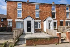 a brick house with a white door and a fence at Family & Group House | 3 Baths | Sleeps 12 in Banbury
