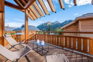 a deck with chairs and a table and mountains at Malago in Le Monêtier-les-Bains
