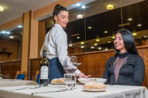 two women sitting at a table with a bottle of wine at Hotel Les Jumeaux Courmayeur in Courmayeur