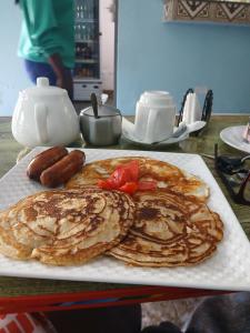 a plate of pancakes and sausage on a table at SolBlu Cottages in Kira