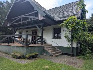 a small white house with a porch and stairs at Czerpak in Małszewko