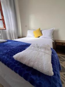 a bed with a blue blanket and a yellow pillow at Hostel dallas Warzazate in Ouarzazate +35 photos