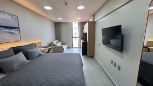 a bedroom with a bed and a television on a wall at Acqua Tambaú Luxury Flat 100 meters from the sea in João Pessoa