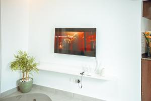 a tv on a white wall in a living room at Résidence Daana in Komé +61 photos
