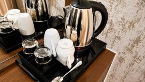 a counter with a coffee pot and glasses on it at Transpark Cibubur by 21room in Kalimanggis