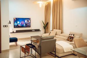 a living room with a couch and a tv on a wall at Résidence Daana in Komé