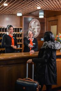 two women standing at a bar with a suitcase at Hotel Les Jumeaux Courmayeur in Courmayeur