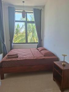 a bedroom with a bed and a large window at Timothe Beach Hotel & Apartments in Song Cau