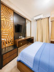a bedroom with a bed and a desk with a television at Transpark Cibubur by 21room in Kalimanggis