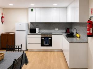a kitchen with white cabinets and a stove top oven at Dona Emília Mercado in Viana do Castelo +12 photos